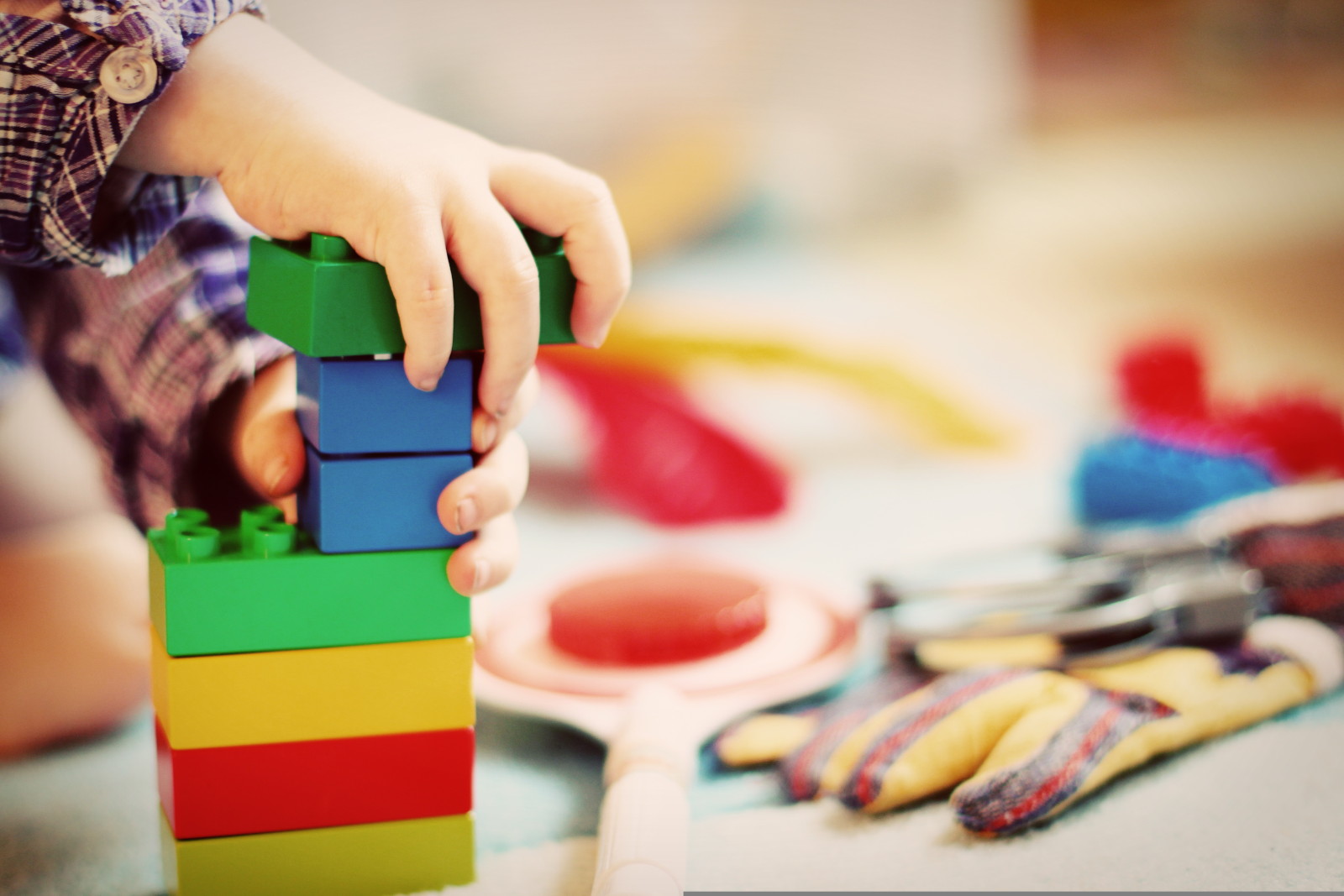 Ein Kind spielt mit bunten Duplo Bausteinen